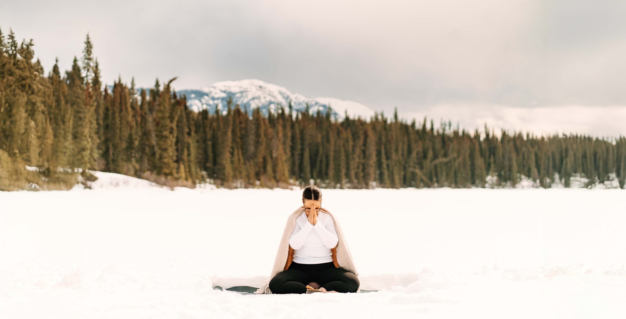 woman sitting cross-legged with prayer hands to forehead.