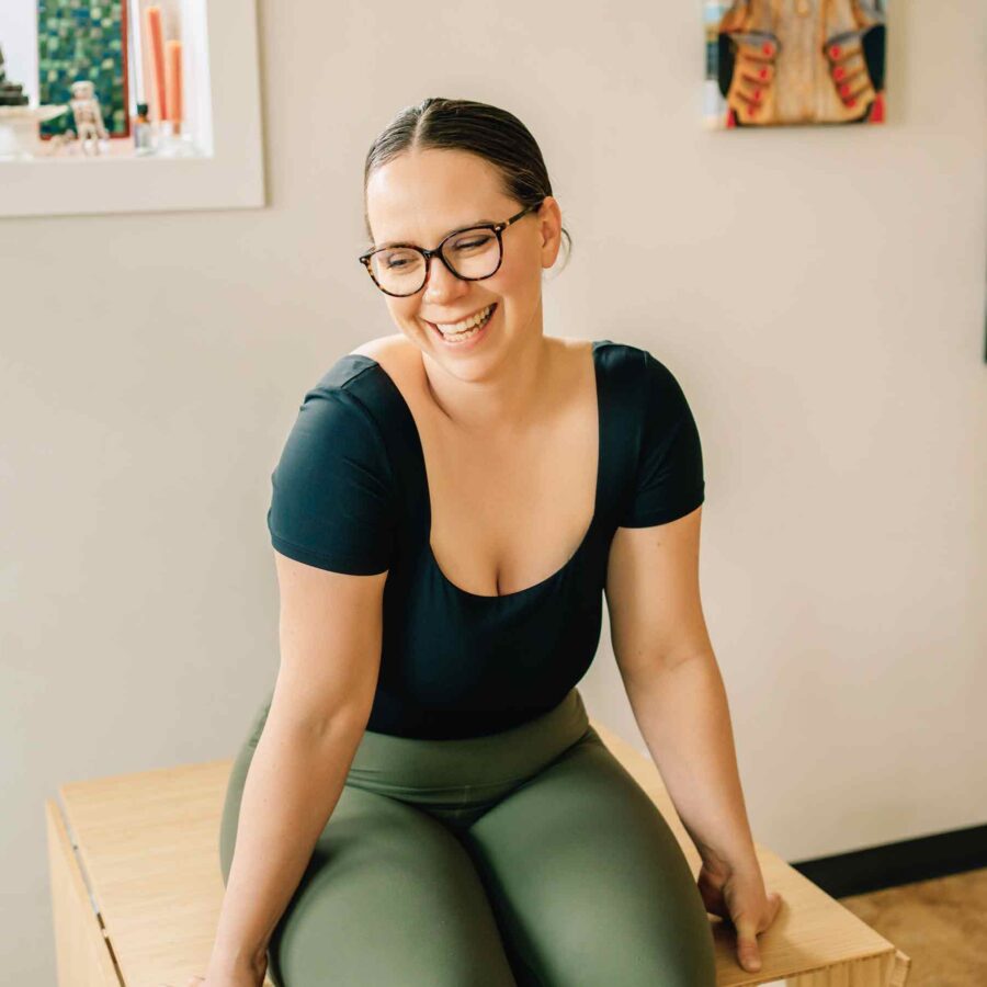 Amitié Yoga - Darci Nyal, E-RYT 500 Sitting on table smiling
