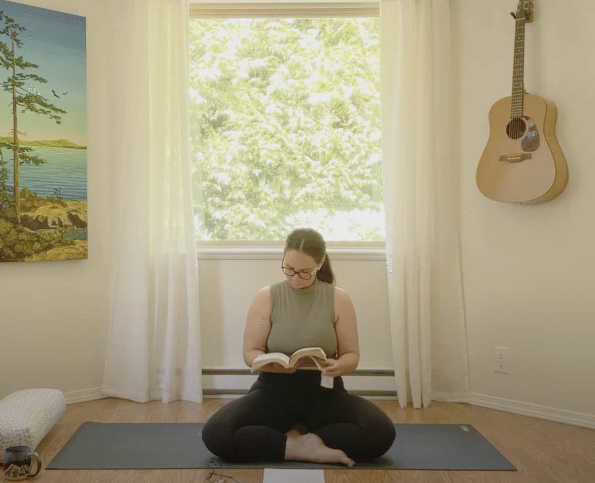 Darci seated on her mat teaching from a book